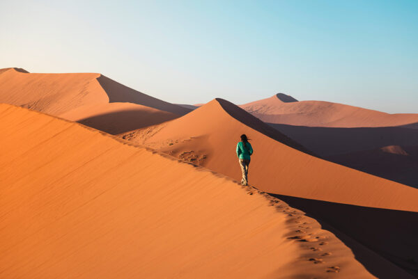Namibia, Namib Desert, Sossusvlei, Woman walking on Dune 45 at sunrise
